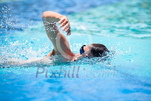 Young man swimming the front crawl in a pool