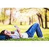 Young woman using her tablet computer while relaxing outdoors in a park on a lovely spring day