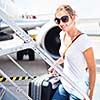 Departure - young woman at an airport about to board an aircraft on a sunny summer day