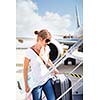 Departure - young woman at an airport about to board an aircraft on a sunny summer day