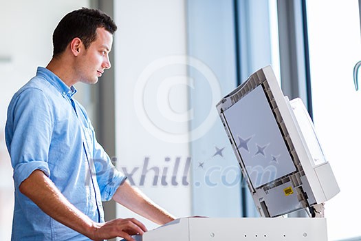 Handsome young man using a copy machine (shallow DOF; color toned image) Handsome young man using a copy machine (shallow DOF; color toned image)