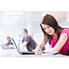 in the library - pretty female student with laptop and books working in a high school library  (color toned image)