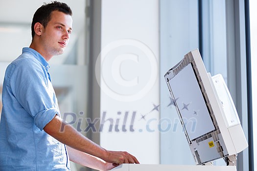 Handsome young man using a copy machine (shallow DOF; color toned image) Handsome young man using a copy machine (shallow DOF; color toned image)
