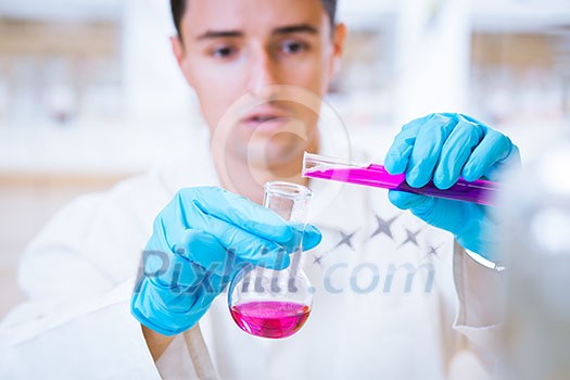 close-up portrait of a young male researcher carrying out experiments in a chemistry research lab (color toned image)