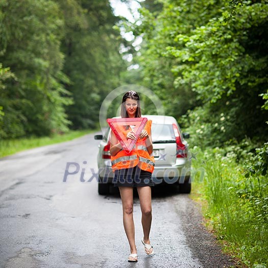 Young female driver wearing a high visibility vest, calling the roadside service/assistance after her car has broken down Young female driver wearing a high visibility vest, calling the roadside service/assistance after her car has broken down