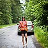 Young female driver wearing a high visibility vest, calling the roadside service/assistance after her car has broken down