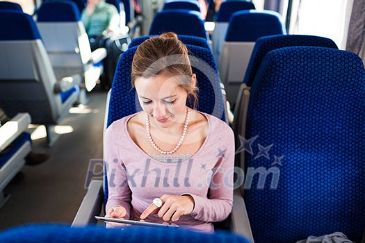 Young woman using her tablet computer while traveling by train Young woman using her tablet computer while traveling by train