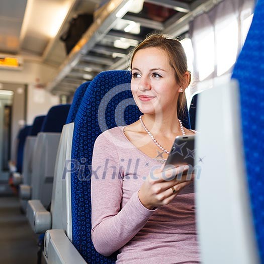 Young woman using her tablet computer while traveling by train Young woman using her tablet computer while traveling by train