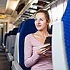 Young woman using her tablet computer while traveling by train