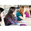 young pretty female college student sitting in a classroom full of students during class