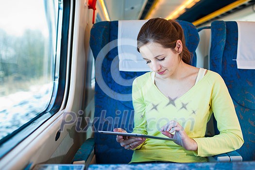 Young woman using her tablet computer while traveling by train Young woman using her tablet computer while traveling by train