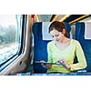 Young woman using her tablet computer while traveling by train