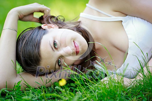 Close-up portrait of an attractive young woman outdoors, lying in the grass, relaxing Close-up portrait of an attractive young woman outdoors, lying in the grass, relaxing