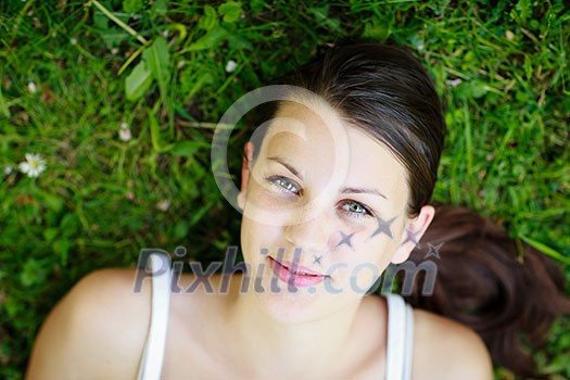 Close-up portrait of an attractive young woman outdoors, lying in the grass, relaxing Close-up portrait of an attractive young woman outdoors, lying in the grass, relaxing