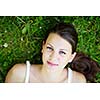 Close-up portrait of an attractive young woman outdoors, lying in the grass, relaxing