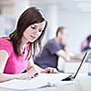 in the library - pretty female student with laptop and books working in a high school library  (color toned image)
