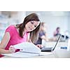 in the library - pretty female student with laptop and books working in a high school library  (color toned image)