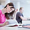 in the library - pretty female student with laptop and books working in a high school library  (color toned image)