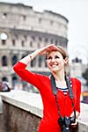 Portrait of a pretty young tourist taking photographs while sightseeing in Rome, Italy (with Colosseum in the background)