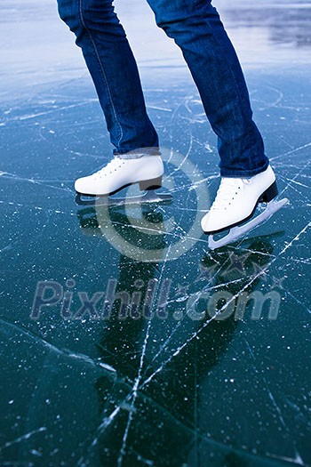 Young woman ice skating outdoors on a pond on a freezing winter day - detail of the legs Young woman ice skating outdoors on a pond on a freezing winter day - detail of the legs