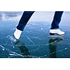 Young woman ice skating outdoors on a pond on a freezing winter day - detail of the legs