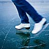 Young woman ice skating outdoors on a pond on a freezing winter day - detail of the legs