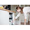 Housework: young woman putting dishes in the dishwasher