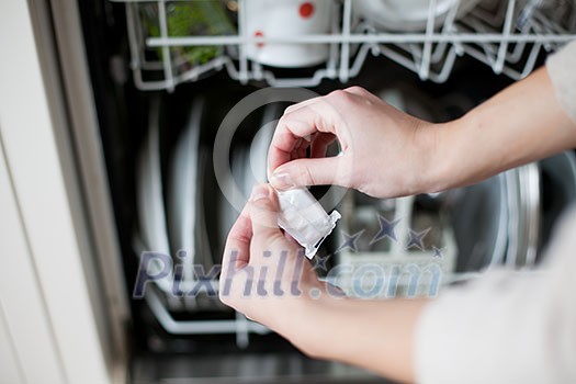 Housework: young woman putting dishes in the dishwasher Housework: young woman putting dishes in the dishwasher