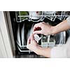 Housework: young woman putting dishes in the dishwasher