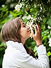 Beautiful young woman smelling white jasmin flowers