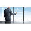 Businessman standing against office window reading documents