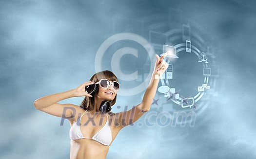 Young attractive girl in bikini wearing headphones touching media icon Young attractive girl in bikini wearing headphones touching media icon