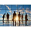 Silhouettes of businesspeople standing against panoramic office window