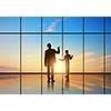 Silhouettes of businesspeople standing against panoramic office window