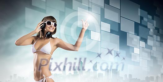 Young attractive girl in bikini wearing headphones touching media icon Young attractive girl in bikini wearing headphones touching media icon