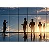 Silhouettes of businesspeople standing against panoramic office window