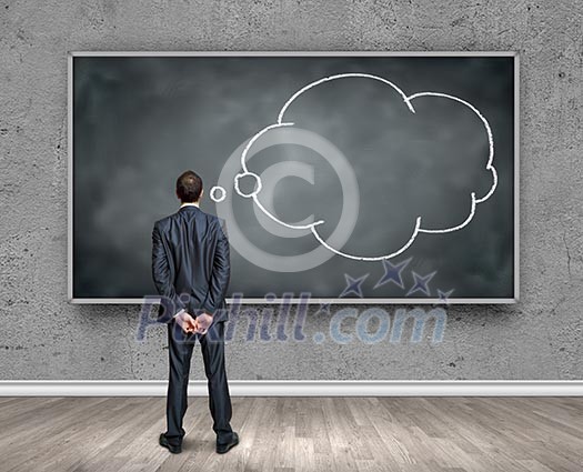 Rear view of businessman looking at chalkboard Rear view of businessman looking at chalkboard