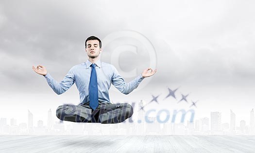 Young businessman sitting in lotus pose and meditating Young businessman sitting in lotus pose and meditating