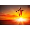 Silhouette of dancer jumping against city in lights of sunrise
