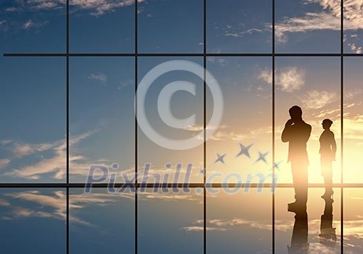 Silhouettes of businesspeople standing against panoramic office window Silhouettes of businesspeople standing against panoramic office window