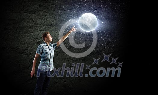 Young man and moon planet against dark background Young man and moon planet against dark background