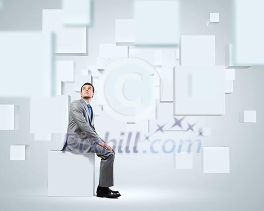 Young handsome businessman sitting on white cube Young handsome businessman sitting on white cube