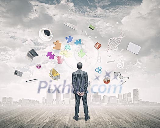 Back view of confident businessman looking at city with items flying in air Back view of confident businessman looking at city with items flying in air