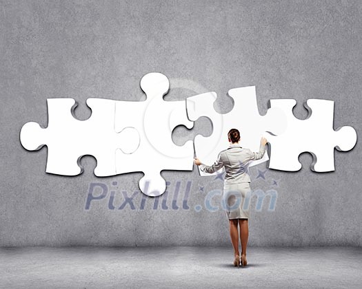 Rear view of businesswoman connecting white puzzle Rear view of businesswoman connecting white puzzle