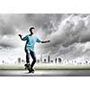 Skater in jeans riding on road against city background
