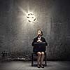 Young businesswoman sitting on chair and looking at dollar symbol above