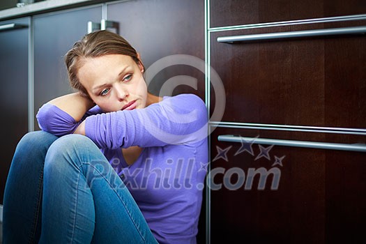 Depressed young woman, sitting on the kitchen floor, feeling down Depressed young woman, sitting on the kitchen floor, feeling down