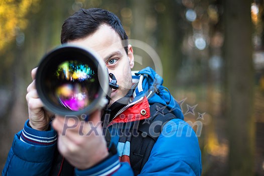 Young, male photographer taking photos with his huge, new, shiny, fast prime professional telephoto lens Young, male photographer taking photos with his huge, new, shiny, fast prime professional telephoto lens