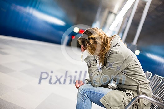 Sad and alone in a big city - Depressed young woman sitting in a metro station, feeling sorrow, regret