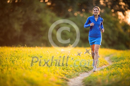 Young woman running outdoors on a lovely sunny summer evening (shallow DOF; color toned image)